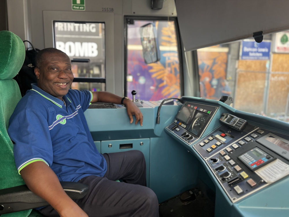 Close-up of London tram driver in uniform at the controls inside a modern tram cab in 2025.
