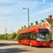 Single decker London bus parked at a bus stop in the city, with passengers waiting to board.