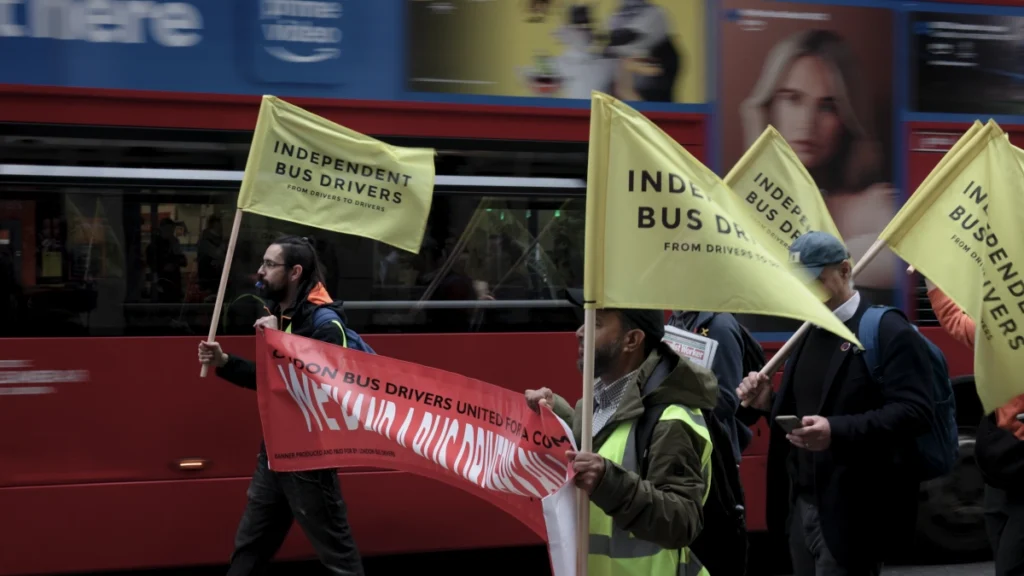 Independent bus drivers carrying yellow flags and a red banner during a demonstration in London.