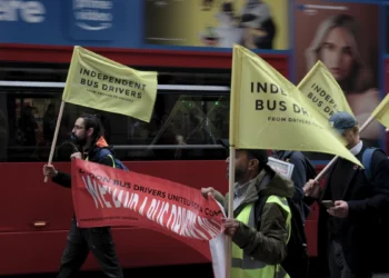 Independent bus drivers carrying yellow flags and a red banner during a demonstration in London.